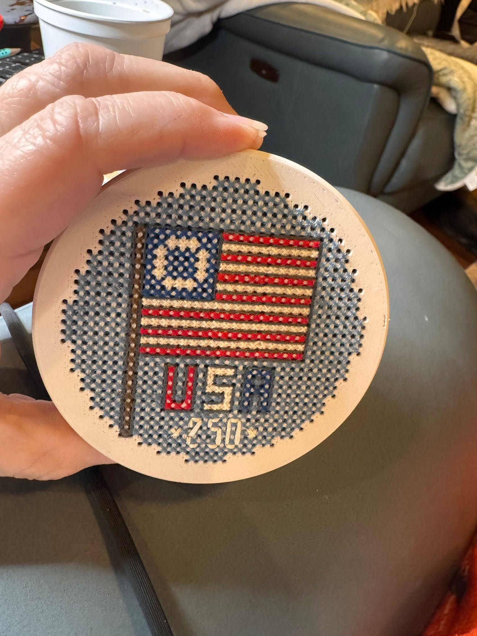 Small 3d printed box held in a hand with a cross stitched USA pattern on it with a flag. 