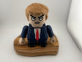 Toy figure of a person in a suit with a red tie on a wooden base against a white background