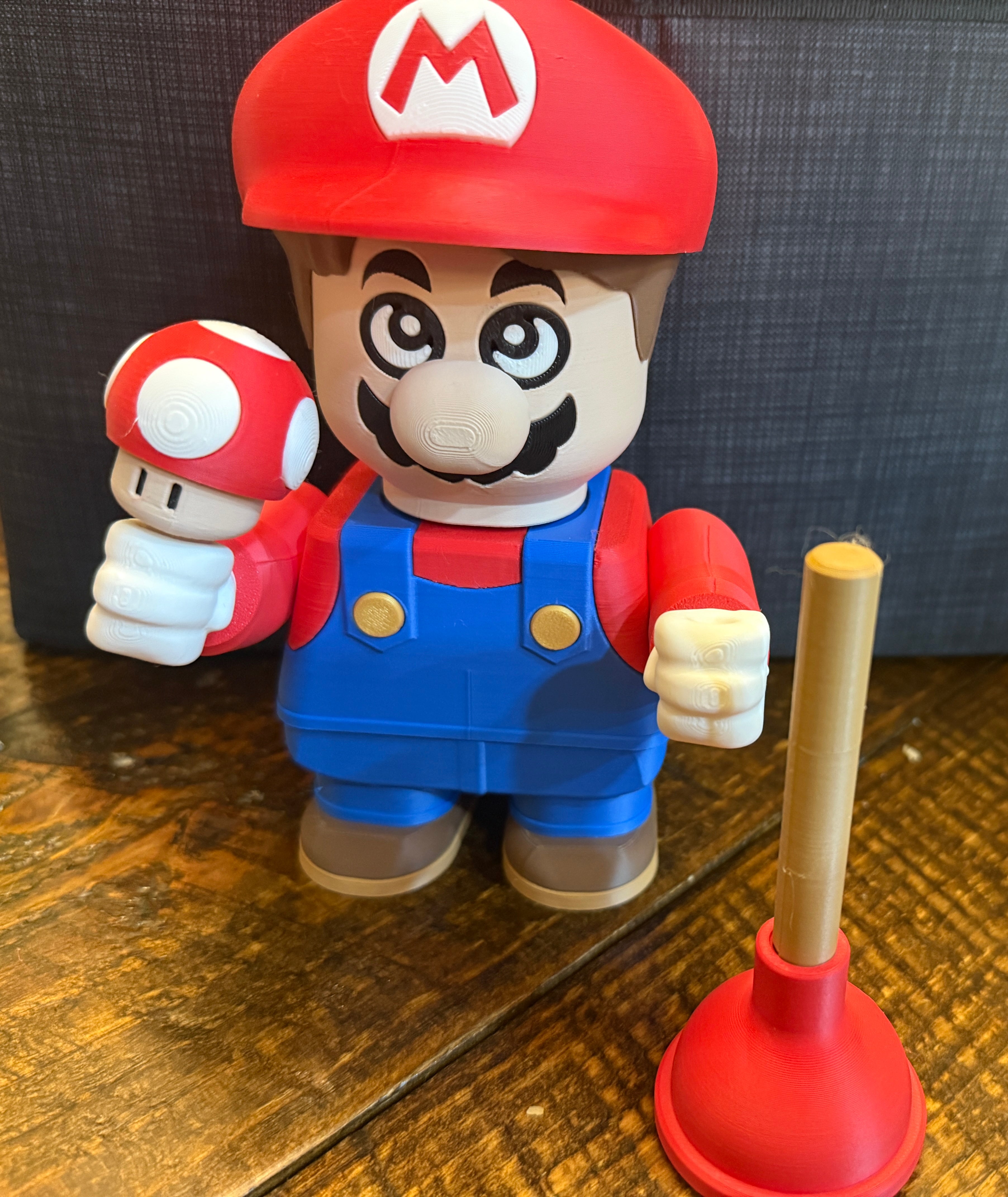 Super Mario figurine holding a mushroom on a wooden surface