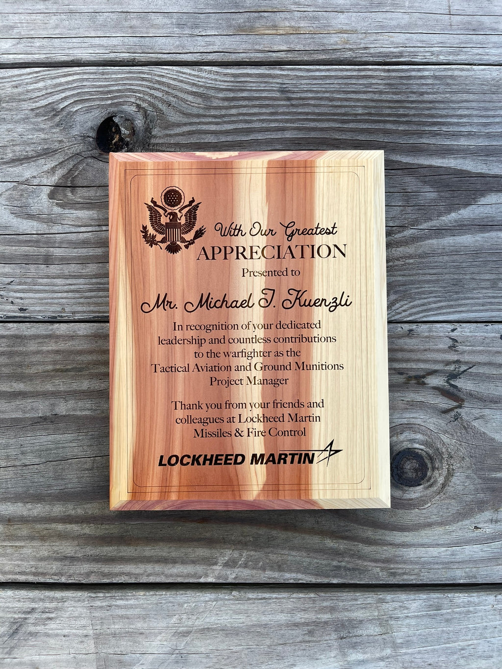 Wooden plaque with engraved text on a wooden surface