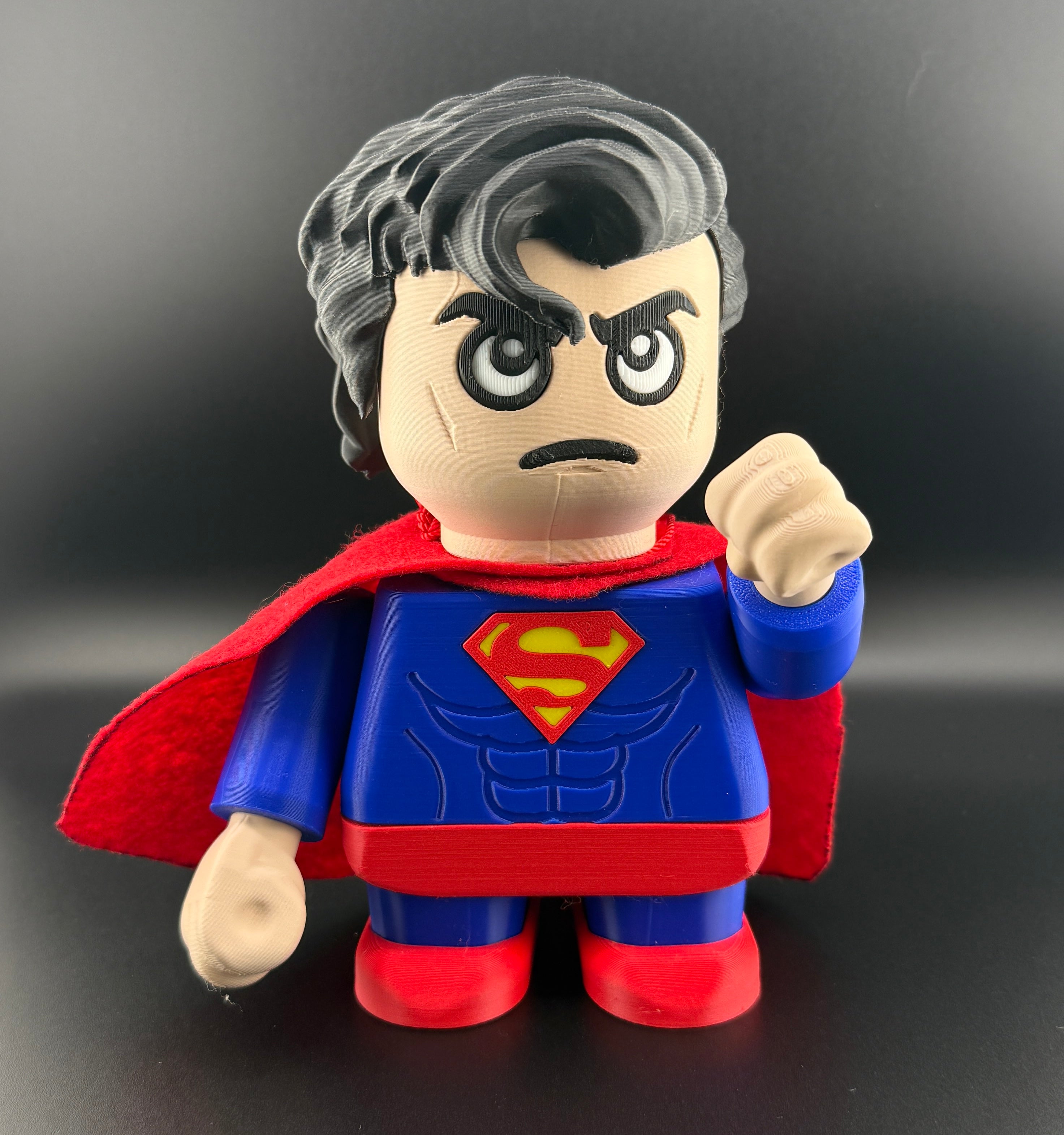 Superman toy figure with red cape and blue suit on a black background