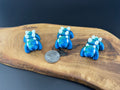 Three small fidget Stegosauruses  on a wooden surface with a coin for scale.