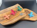 Three small fidget pteradactyls  on a wooden surface with a coin for scale.