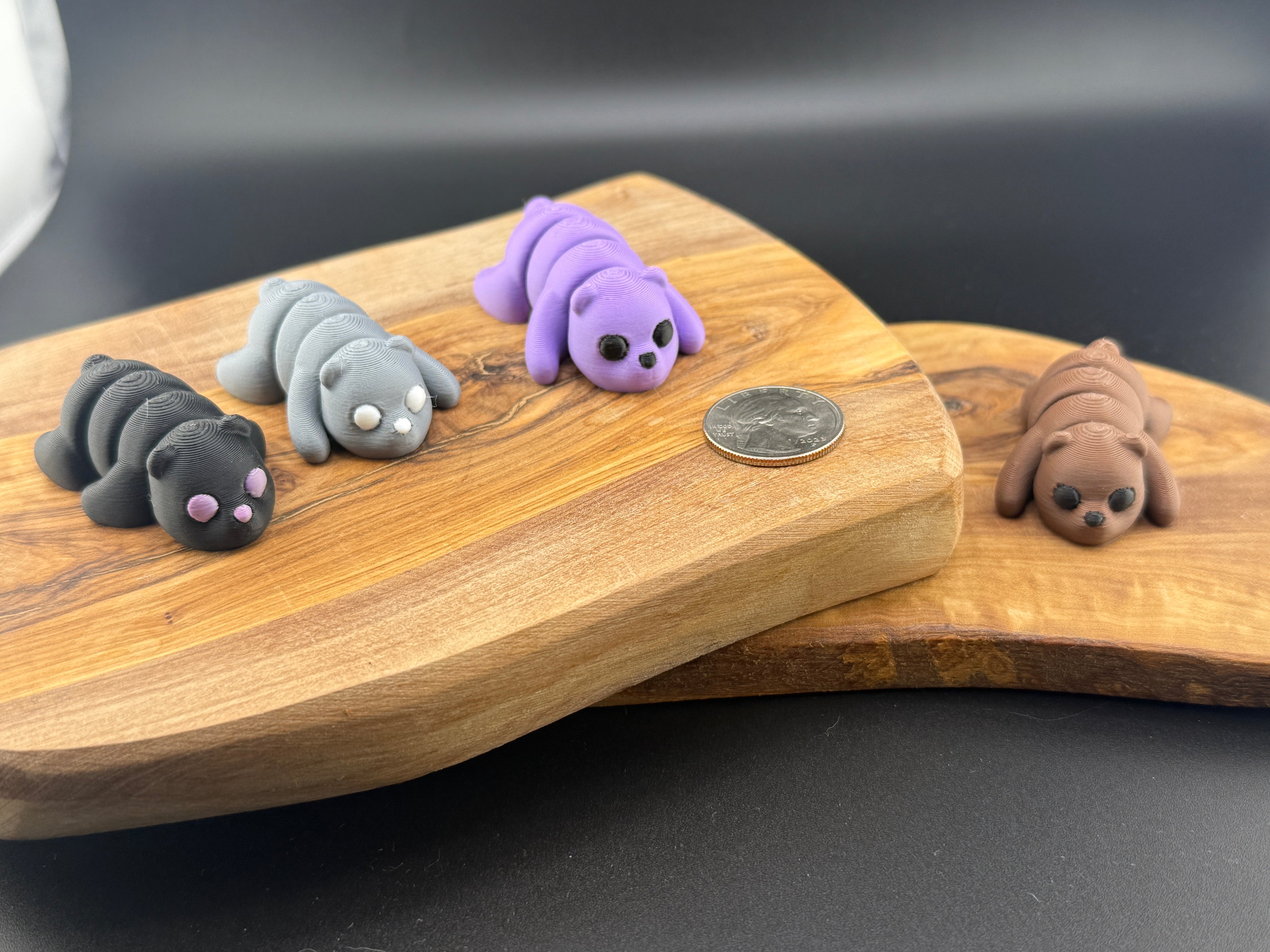 Three small fidget bears  on a wooden surface with a coin for scale.