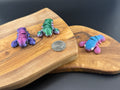 Three small fidget lobsters  on a wooden surface with a coin for scale.