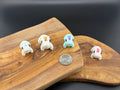 Four small fidget unicorns  on a wooden surface with a coin for scale.