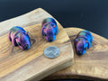Three small fidget rhinos  on a wooden surface with a coin for scale.