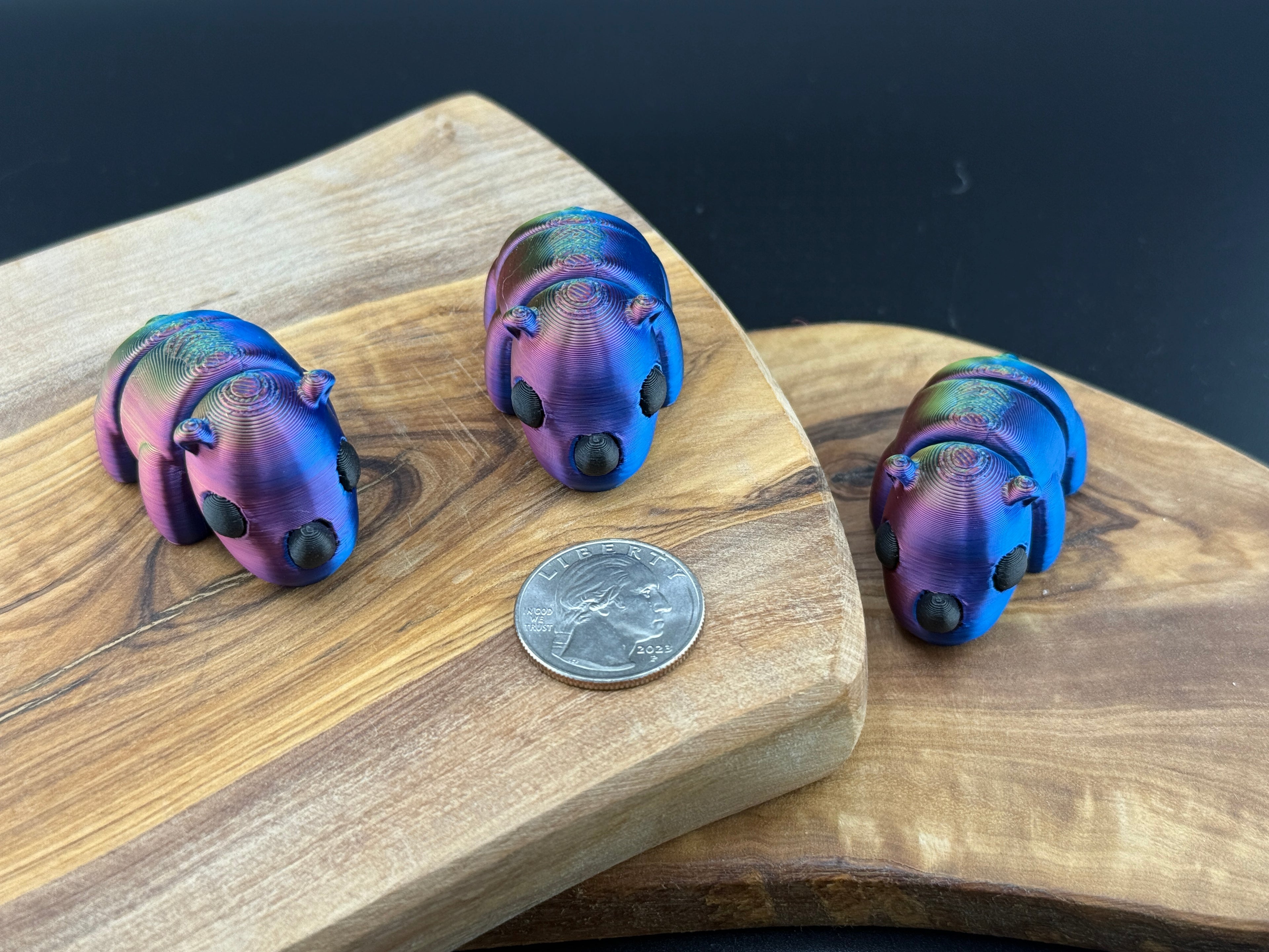 Three small fidget rhinos  on a wooden surface with a coin for scale.