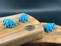 Three small fidget dogs on a wooden surface with a coin for scale.