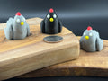 Three small fidget chickens on a wooden surface with a coin for scale.
