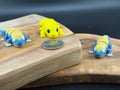 Three small fidget leopard geckos  on a wooden surface with a coin for scale.