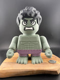 Toy figure with a gray head and purple shorts on a wooden board