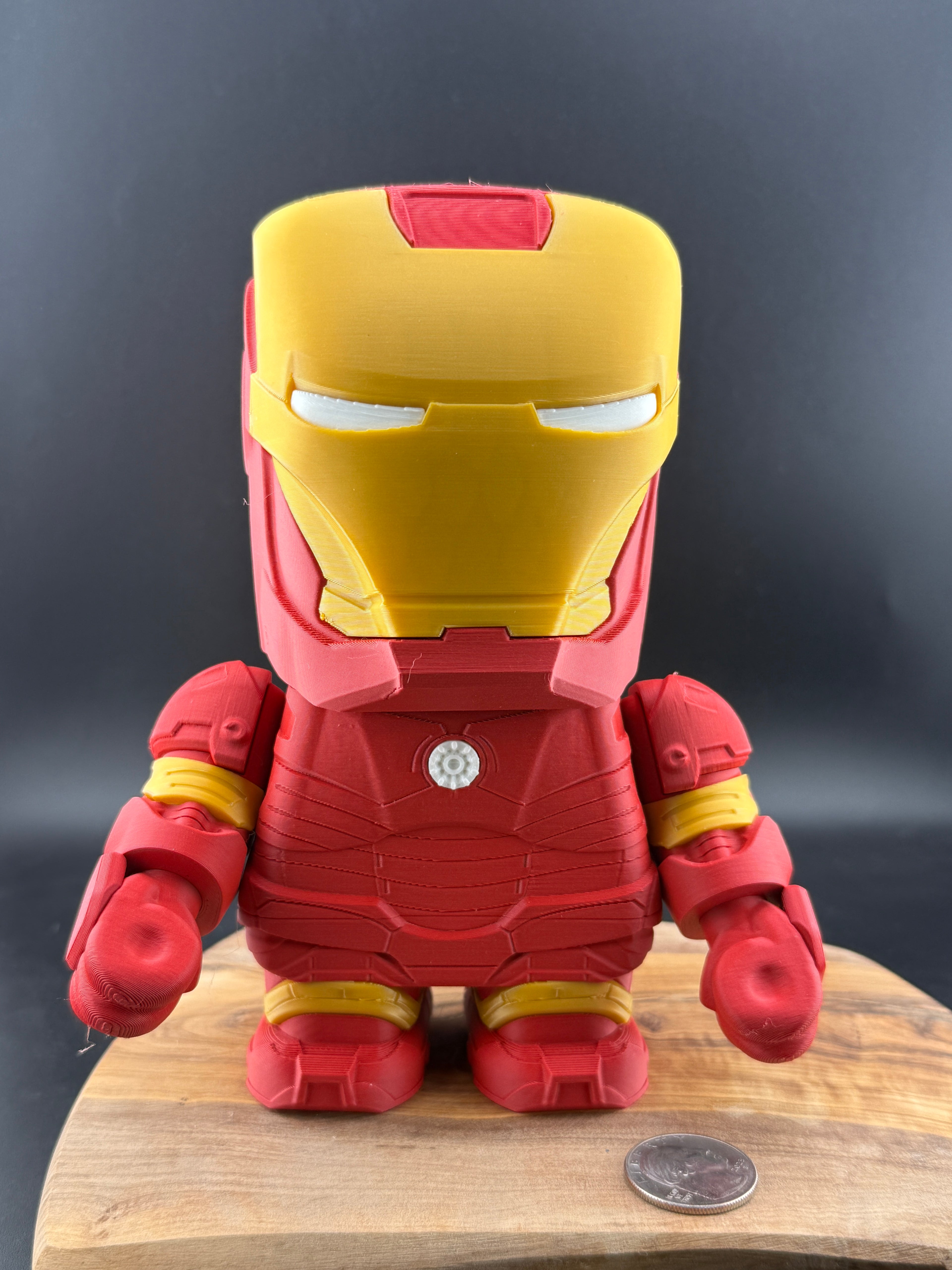 Toy figure of a superhero in red and yellow on a wooden surface with a dark background