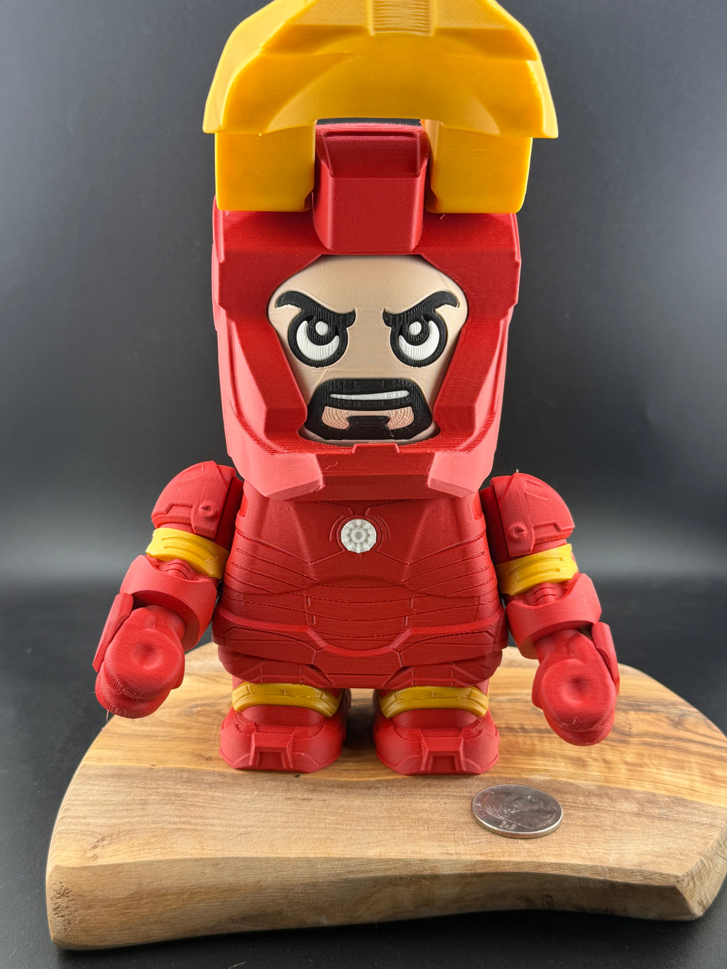 Toy figure of a character in red and yellow armor on a wooden stand with a dark background mask up. 