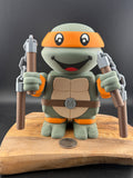 3D Printed turtle figure with orange shell on a wooden base against a dark background