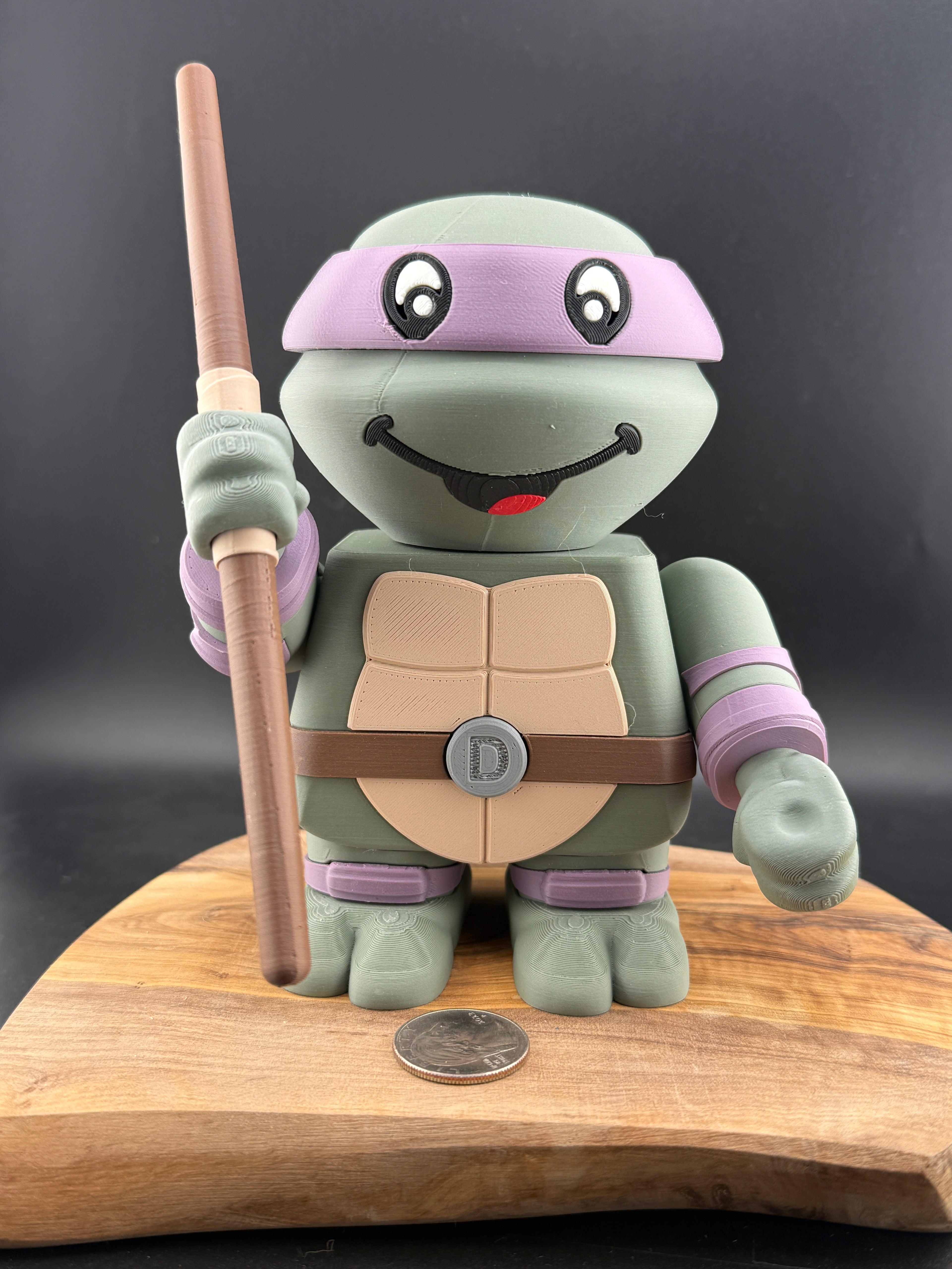 3D Printed turtle with a staph on a wooden platform against a dark background