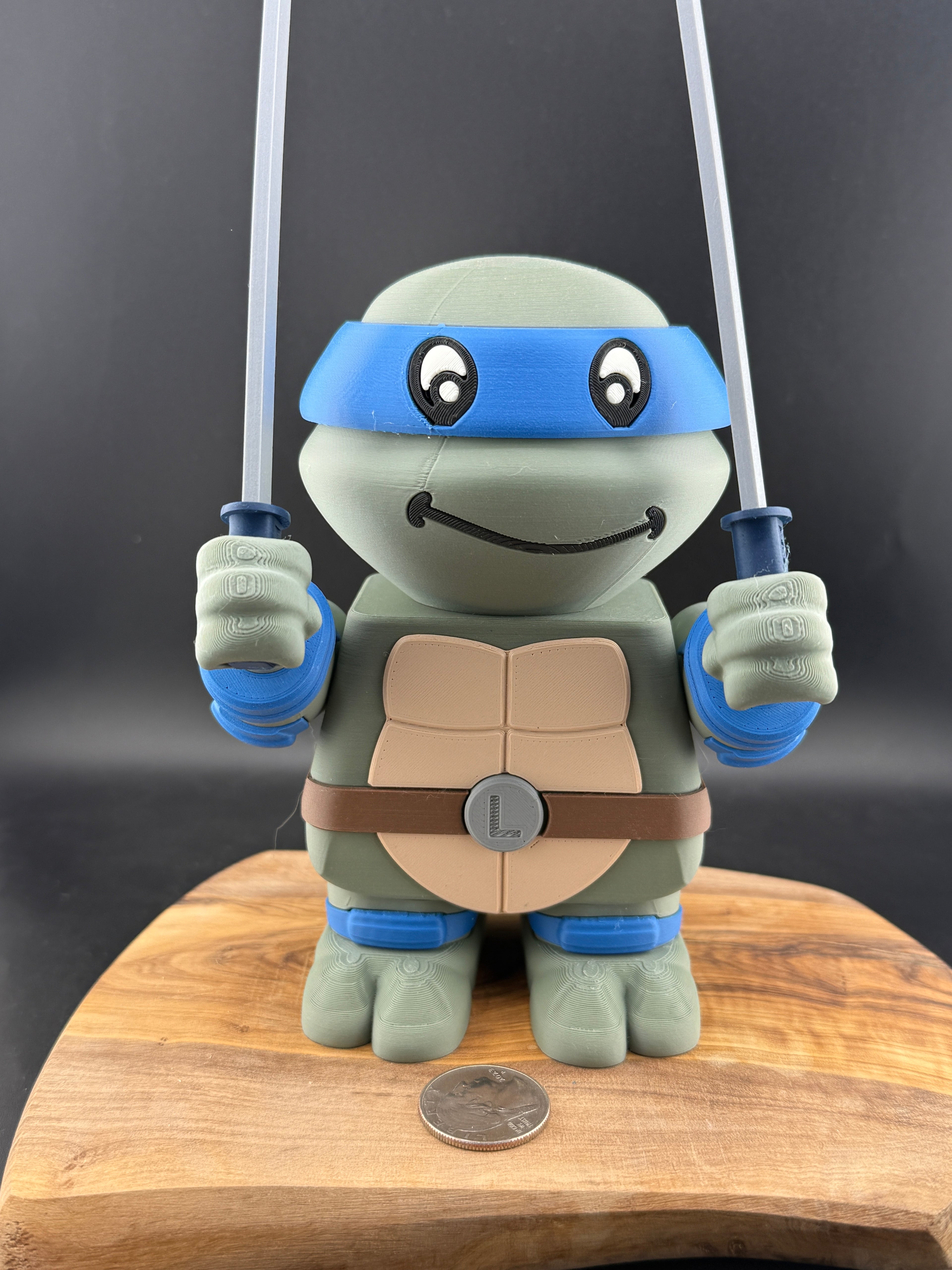 3D printed toy turtle with blue masks and weapons on a wooden surface
