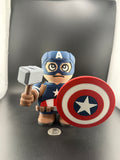 Toy figure of a superhero holding a hammer and shield on a dark background