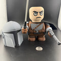 Toy figure of a character from a popular franchise on a dark surface with a coin for scale.