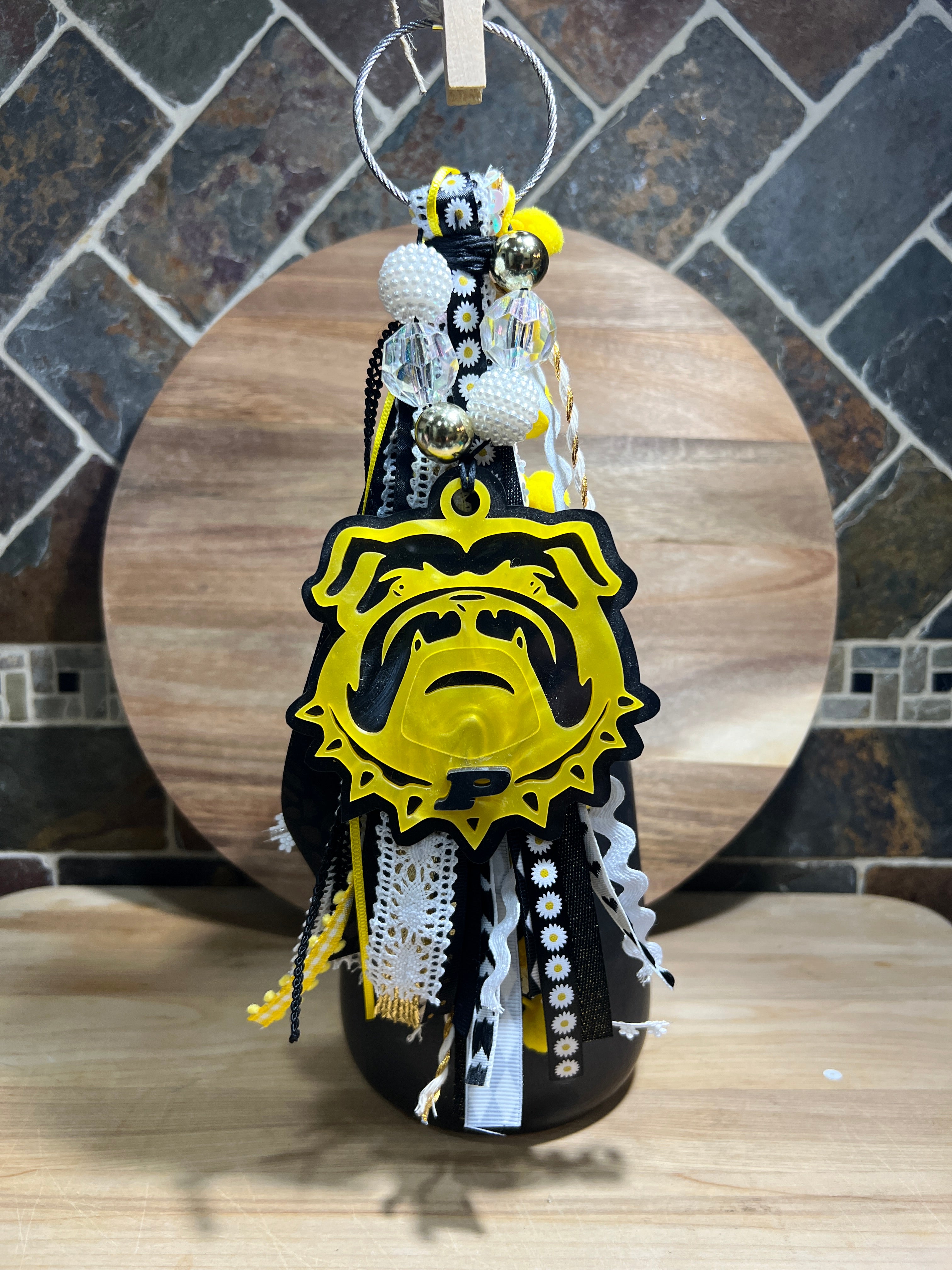 Decorative bag tag with yellow and black ribbon, made of acrylic on a wooden background. 