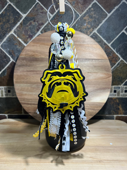 Decorative bag tag with yellow and black ribbon, made of acrylic on a wooden background. 