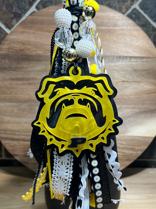 Decorative bag tag with yellow and black ribbon, made of acrylic on a wooden background. 