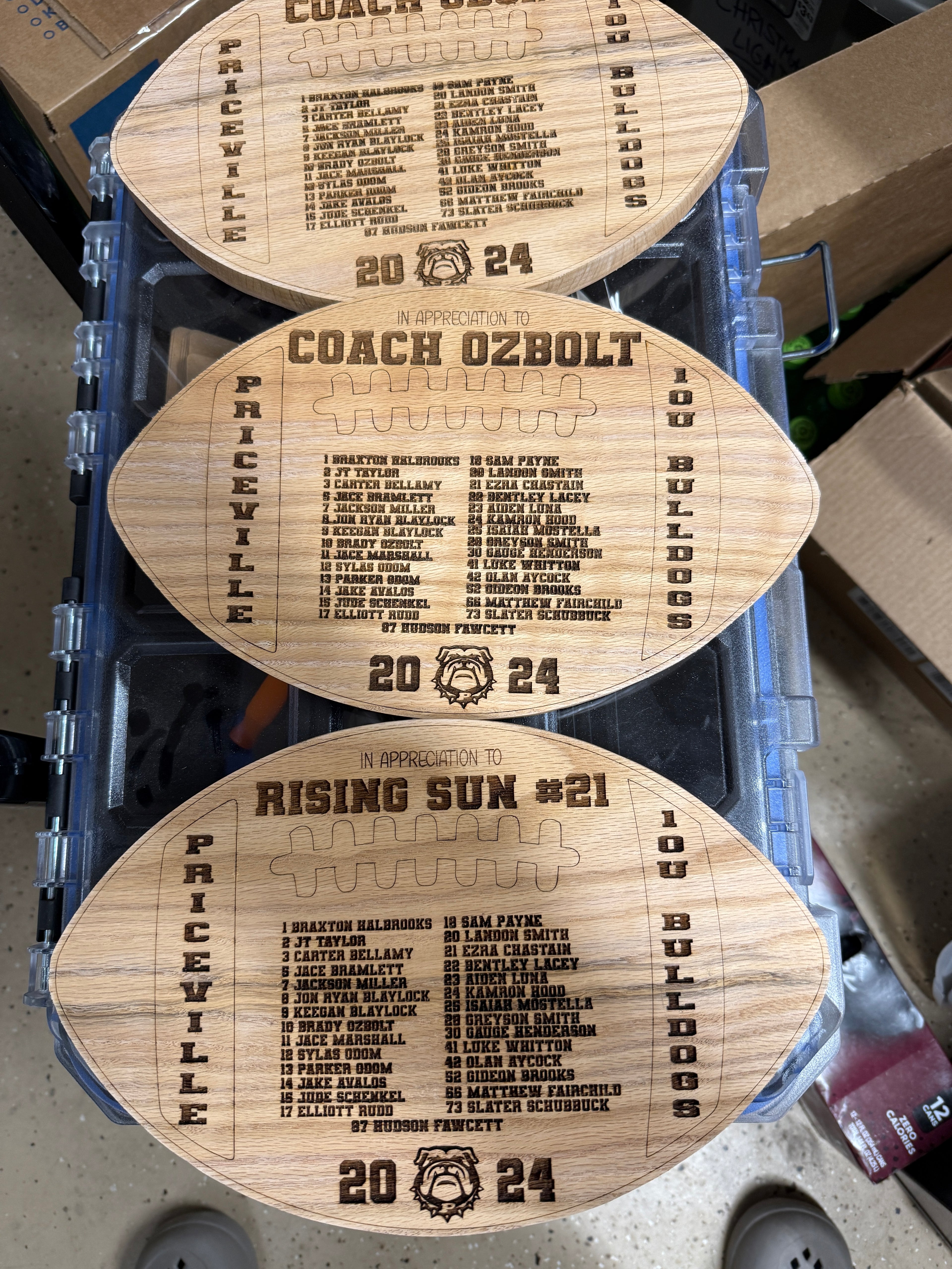 Three wooden shaped footballs with engraved text. 